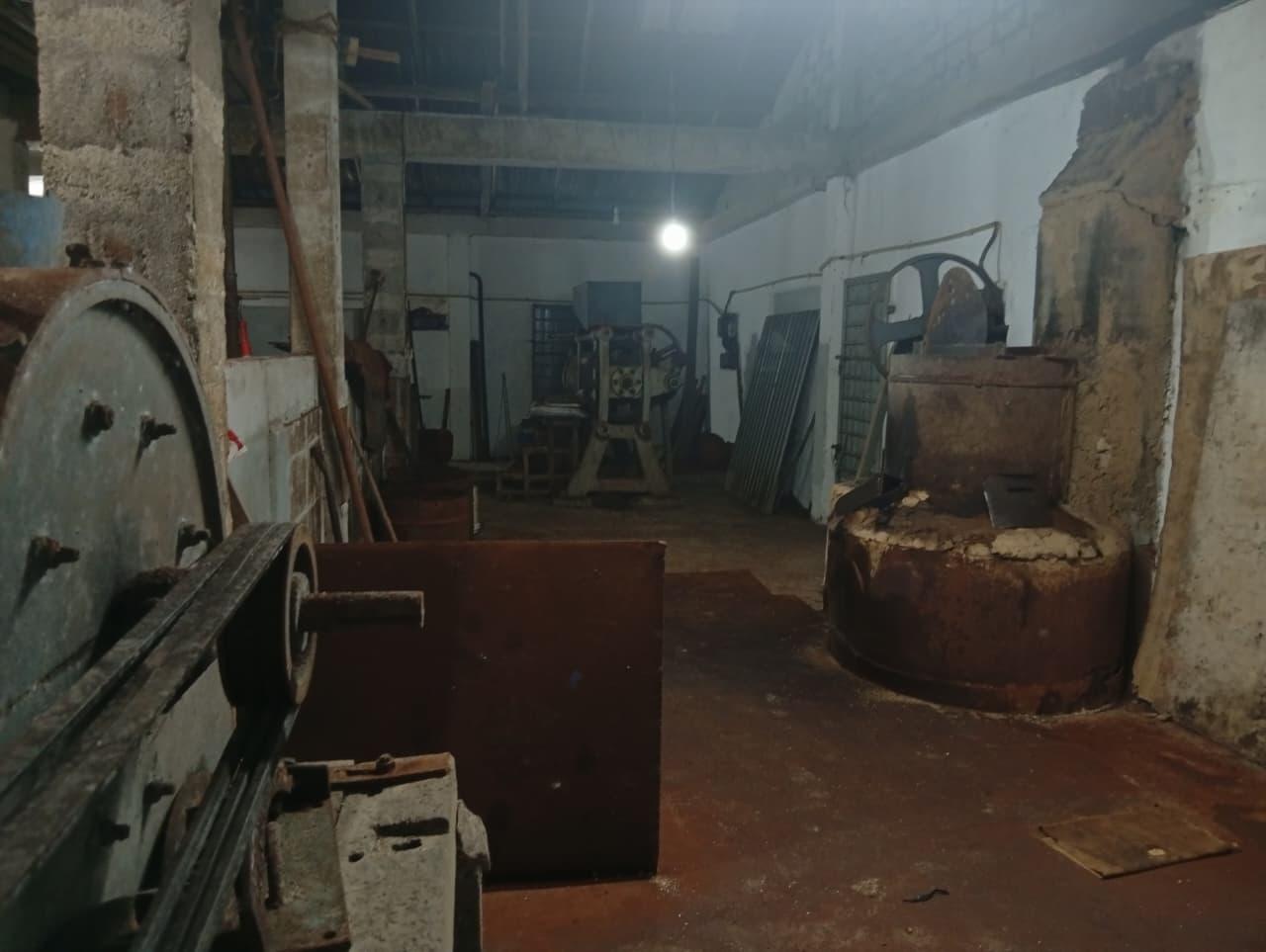 Inside our mill: old belt-driven machinery and a large vat under a single bulb